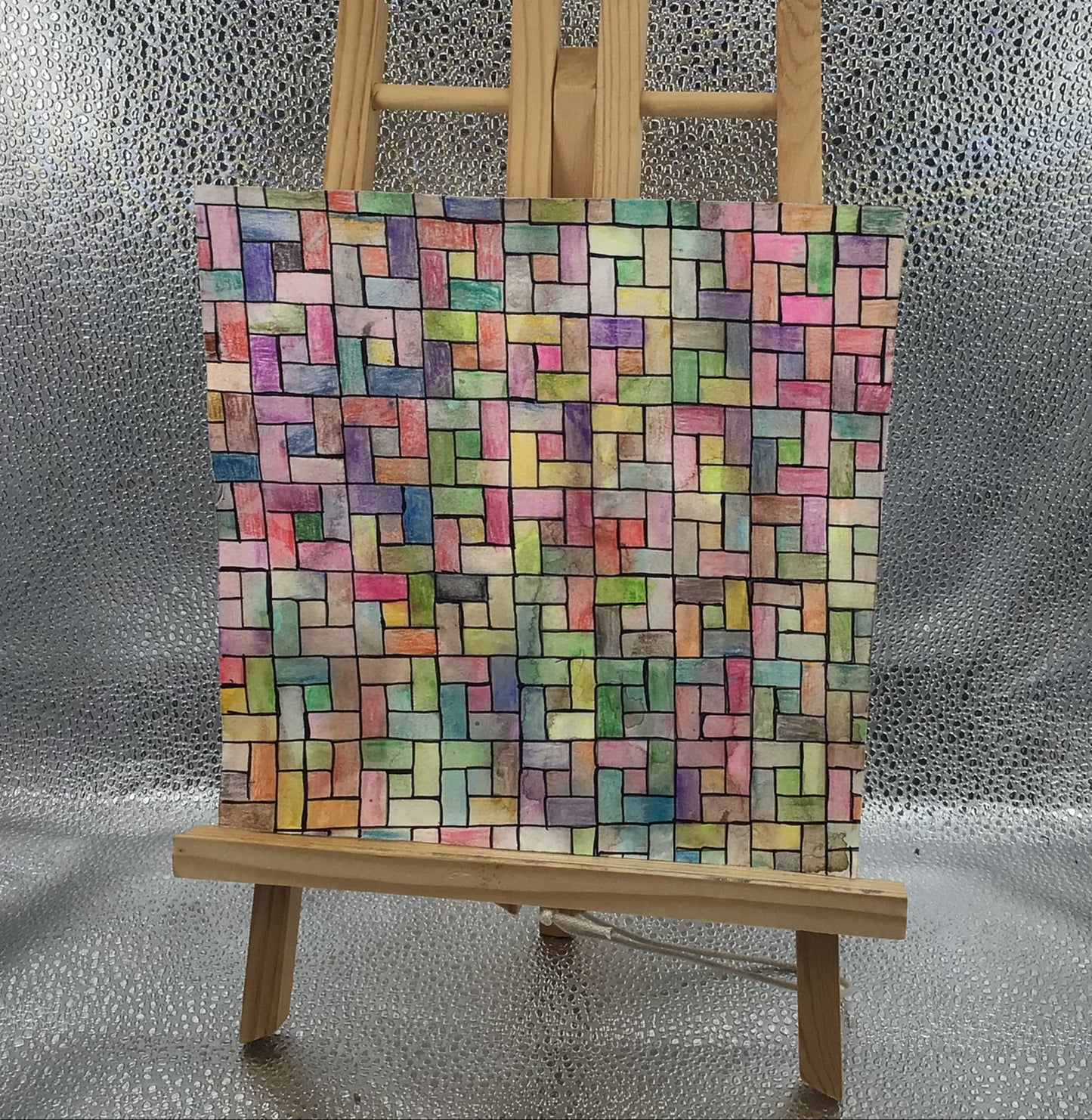 Colorful brick-patterned board on a wooden stand against a textured silver background