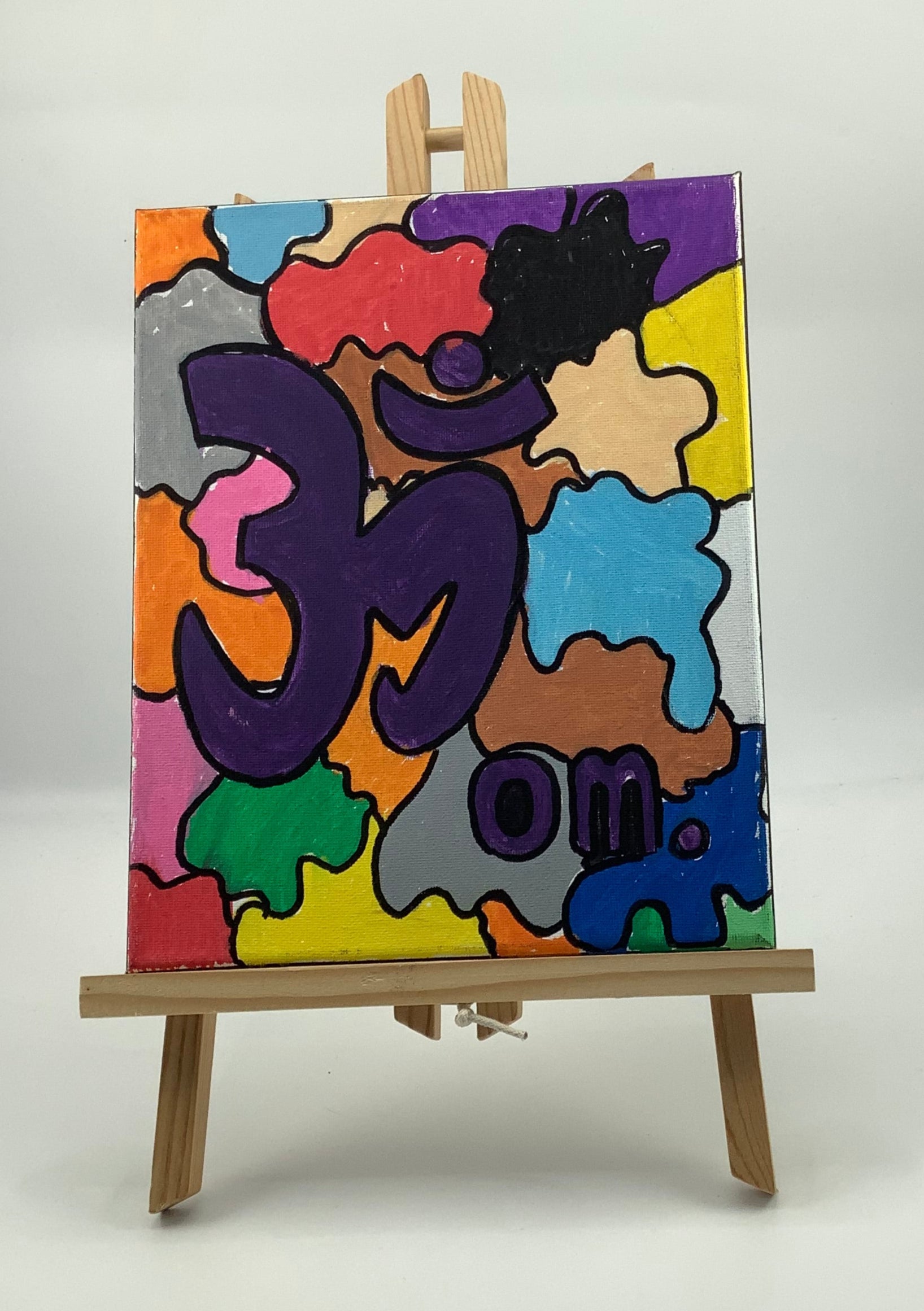Colorful abstract painting on an easel against a white wall